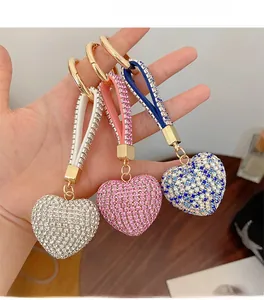 Detailed view of hand holding sparkling heart-shaped rhinestones keychains in three colors
