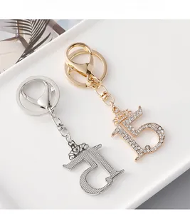 Close-up of number 15 metal keychains with crown design and sparkling white rhinestones