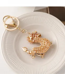 Détail d'un porte-clés dragon doré orné de strass blancs sur une assiette en céramique