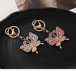 Detailaufnahme der Strass-Schmetterling-Schlüsselanhänger in Pink und Silber auf Tablett