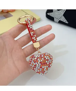 Detailed view of luxury red rhinestone heart keychain with gold ring on a handbag