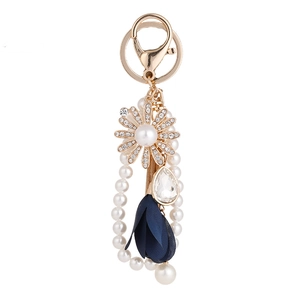 Elegant gold keychain featuring rhinestone sunflower, white pearls, and a navy blue tassel charm