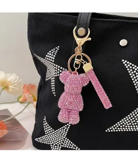 Close-up of a pink rhinestone bear charm with golden clip on a black canvas bag