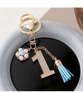 Vue macro du porte-clés doré avec numéro 1, fleur de perles et pompon bleu