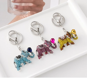 Detailed macro view of three crystal-encrusted elephant keychains in blue, pink and amber