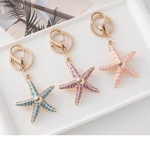 Detail of starfish keychains in blue, purple, and pink with golden metal finish