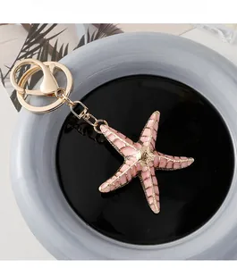 Detailed macro view of pink enamel starfish keychain with golden metallic edges