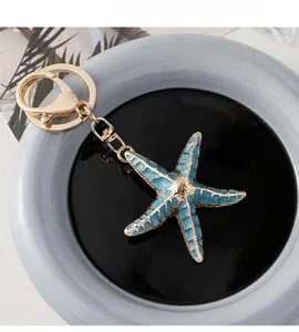 Detail view of a gold starfish keychain with light blue checkered enamel filling on a tray