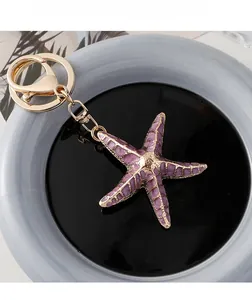Detailed view of starfish keychain with purple enamel finish and golden metal link chain