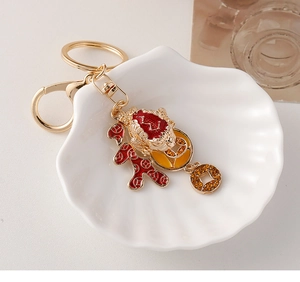 Detail of golden Chinese lucky toad keychain with red enamel and amber rhinestones