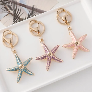 Starfish and seashell metal keychains in blue, purple, and pink on a white tray