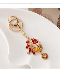 Detailed close-up of a golden Chinese lion dance keychain with red enamel and lucky coins