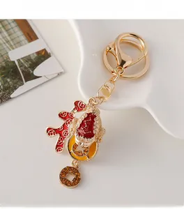 Detail of a golden Chinese toad keychain with red enamel and lucky coin charms