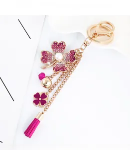 Detail of four-leaf flower keychain with pink rhinestones, pearl, and metallic tassels