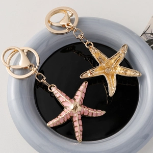 Starfish ocean keychain set with gold plated finish and pink enamel detailing on a tray