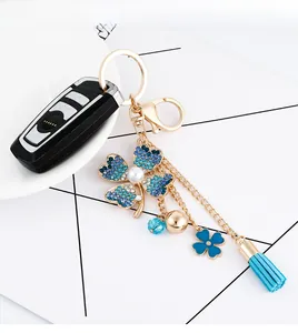 Detail of four-leaf flower keychain with blue rhinestones, pearl, and suede tassel