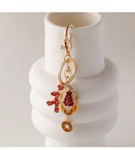 Detail of a golden keychain featuring red enamel Ruyi charms and a yellow gemstone coin