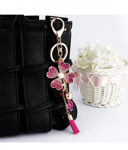 Detailed view of pink rhinestone flower keychain with silk tassel on a black woven bag