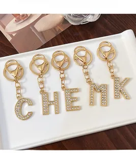 Detail view of gold alloy alphabet keychains with white rhinestones on ceramic tray