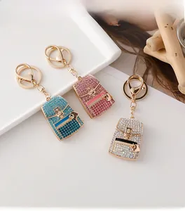 Detailed close-up of mini backpack keychains in blue, pink, and white with sparkling rhinestones