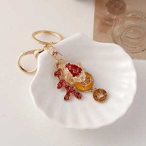 Golden Chinese lucky toad keychain with red enamel and crystals on a white plate