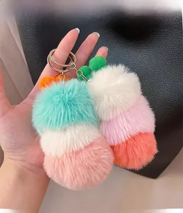 Detail of colorful fluffy plush ball keychains with metallic rings on a black bag
