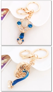 Macro detail of gold Ruyi keychain featuring blue rhinestones and moonstone inlay