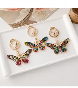 Détail de trois porte-clés papillon avec strass colorés sur une base en alliage doré