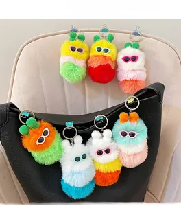 Close-up of colorful plush caterpillar keychains with sunglasses hanging on a leather bag
