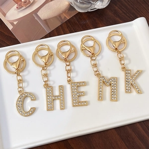 Golden alloy alphabet keychains with rhinestone inlay C H E M K styles on a ceramic tray