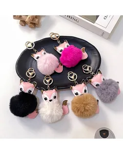 Dettaglio di sei portachiavi a pompon con volpe di peluche in vari colori su un tavolo bianco