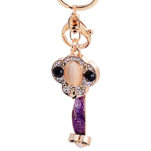 Golden Ruyis key ring with moonstone inlay and purple enamel detailing on white background