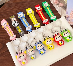 Set of six colorful cartoon zodiac dragon keychains with silicone wrist straps in a ceramic dish