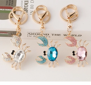 Détail de trois porte-clés crabe ornés de cristaux en argent, bleu et rose brillant