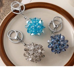 Détail de porte-clés boule en cristal scintillant bleu et gris sur une assiette en céramique