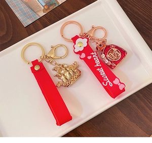 Detail of red silicone wristlet with gold dragon charm and fortune bag keychain pendant