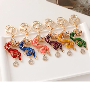 Detailed set of six colorful dragon keychains with rhinestones on a white tray