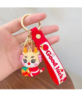 Close-up of cartoon dragon keychain with red Good Luck strap and golden hardware