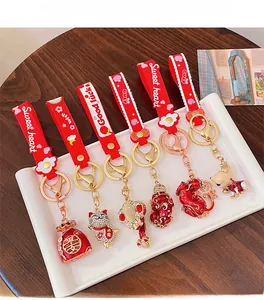 Detail of red festive keychains featuring lucky cat and fortune bag charms on a white tray