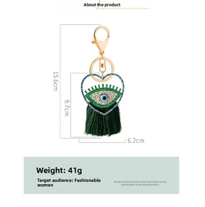 Détail du porte-clés œil protecteur avec cadre en cœur, pompon vert et dimensions de 15,6 cm