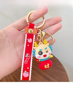 Close-up of a cartoon dragon keychain with a red lucky bag and patterned wrist strap