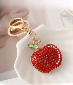 Macro view of red rhinestone apple keychain with gold horseshoe buckle on ceramic plate