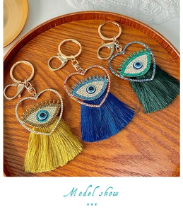 Détails macro des porte-clés cœur Evil Eye avec strass et pompons en soie longs