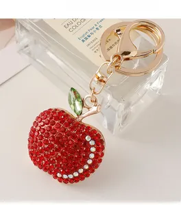 Close-up of red rhinestone apple keychain with green leaf and golden metal hardware