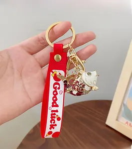 Close-up of a festive fish keychain with 'Good luck' silicone strap and gold metal hook