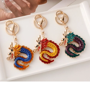 Detailed view of three colorful enamel Chinese dragon keychains in a white ceramic tray