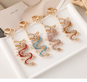 Détail de quatre porte-clés dragon avec strass colorés et perles d'imitation