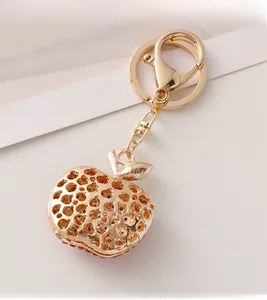 Detail of apple keychain with golden hollow heart patterns and red crystal accents