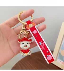 Detail of red cartoon pig keychain with rhinestone dress and silicone wrist strap
