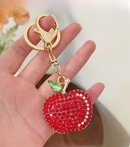 Detailed view of the sparkling red rhinestone apple keychain with gold metal clasp and ring